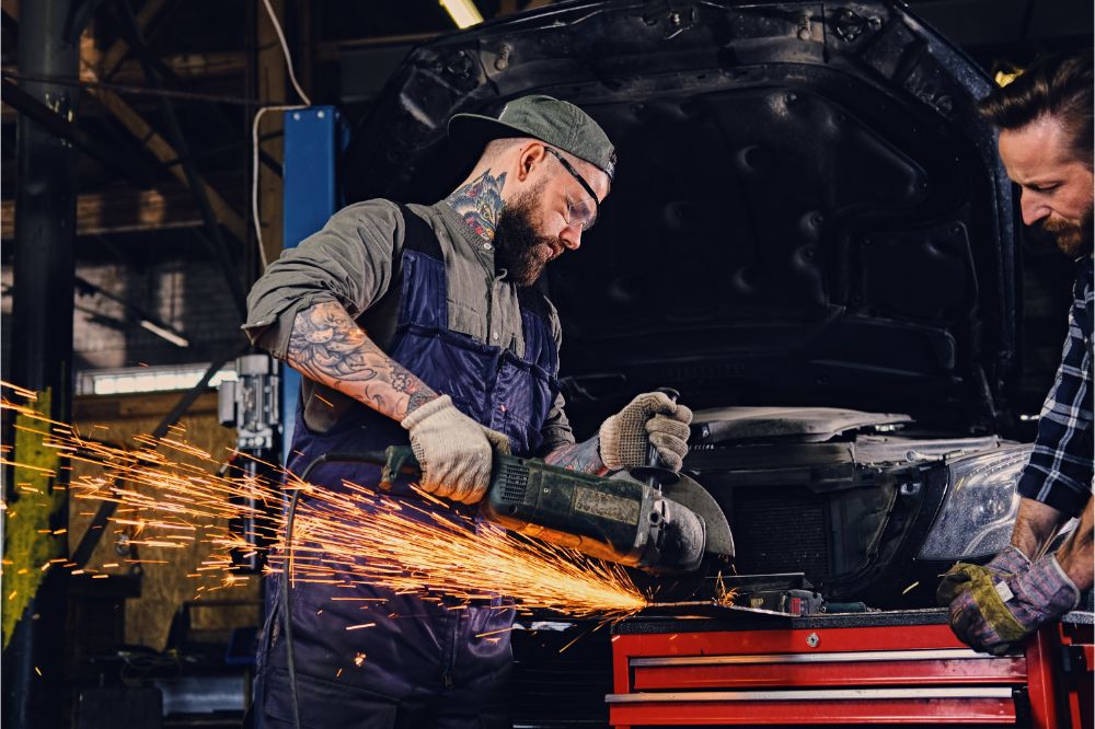 mechanics working with an angle grinder in a garage