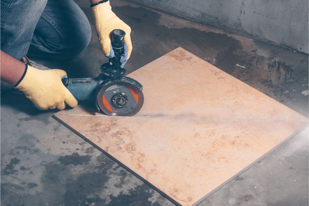 working tiler cuts the tile with angle grinder