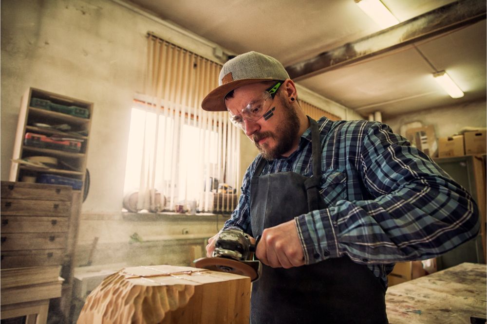 guy with angle grinder carving wood